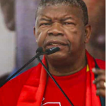 João Lourenço discursa em acto político do MPLA, usando vestuário vermelho do partido, durante um evento relacionado à sua recandidatura à liderança partidária em Angola.